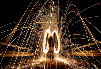 Man creating rotating and swirling sparks in a dark place