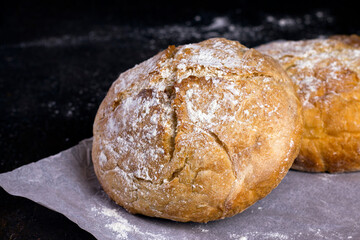 Fresh homemade crisp bread. Healthy baked bread on Kraft paper over black rustic wooden table.