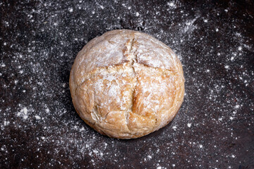 Fresh homemade crisp bread on black wooden table with wheat flour. Healthy baked bread. Traditional bakery Rustic style concept.