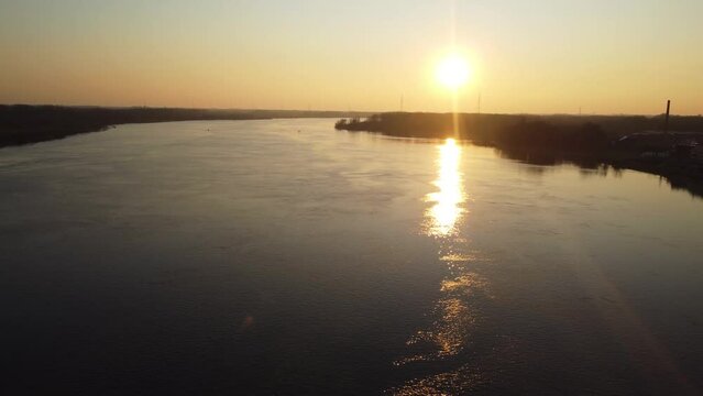Silhouette of small town during bright golden sunset near river Scheldt, aerial view