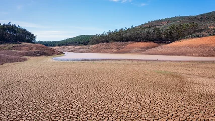 Zelfklevend Fotobehang Landscape of low water and dry land in advance, severe drought in the reservoir of Portugal. Ecological disaster, soil dehydration. desert, drought, © sergojpg