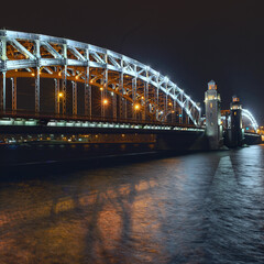 the beautiful metal bridge of Peter the Great across the Neva River in St. Petersburg against the night sky
