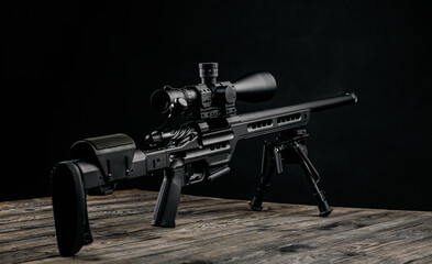Modern powerful sniper rifle with a telescopic sight mounted on a bipod. Dark back.