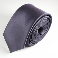 black colour polyester fabric necktie rolled on white background close-up view single object 