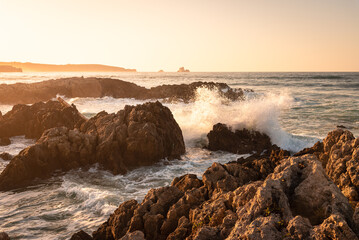 Rough sea waves hit the rocks at the famous surfing beach of Canallave at sunset, Dunas de Liencres Natural Park and Costa Quebrada, Cantabria, Spain