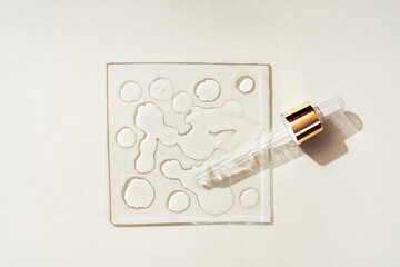 Drops of cosmetic product or liquid transparent gel with bubbles near a pipette on a light beige...