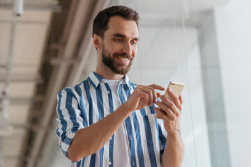 Young smiling bearded man using mobile phone communication, online shopping