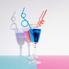 Tropical red Sangria and Blue Lagoon cocktail on pastel pink and blue background. Summertime, beach and nightlife concept.