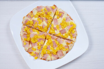 Traditional Hawaiian pizza, with cheese, pineapple, pomodoro pasta on checkered napkin