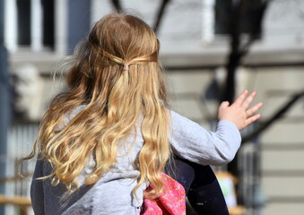 Kind mit langen blonden Haaren auf Beobachtungsposten der Welt zuwinkend