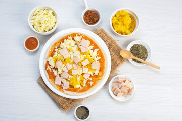 Artisan pizza before baking, with cheese, ham, pineapple, pomodoro sauce, accompanied by flavors