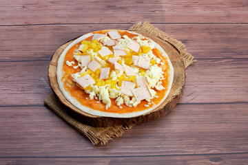 Artisan pizza before baking, with cheese, ham, pineapple, pomodoro sauce, accompanied by flavors