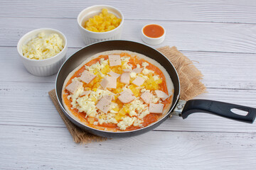 Artisan pizza before baking, with cheese, ham, pineapple, pomodoro sauce, accompanied by flavors