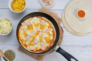 Artisan pizza before baking, with cheese, ham, pineapple, pomodoro sauce, accompanied by flavors