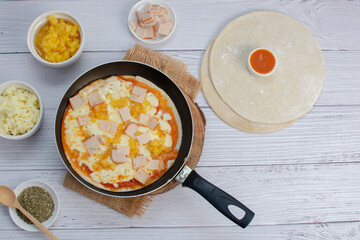 Artisan pizza before baking, with cheese, ham, pineapple, pomodoro sauce, accompanied by flavors