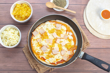 Artisan pizza before baking, with cheese, ham, pineapple, pomodoro sauce, accompanied by flavors