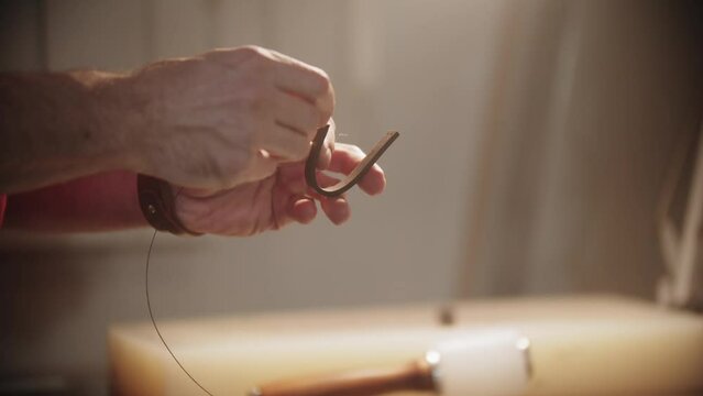 A man sews the belt loop with thick thread