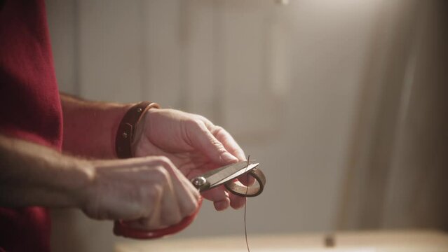 A man cuts the thread after finishing sewing the belt