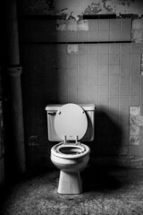Vertical shot of a scary toilet in black and white in prison