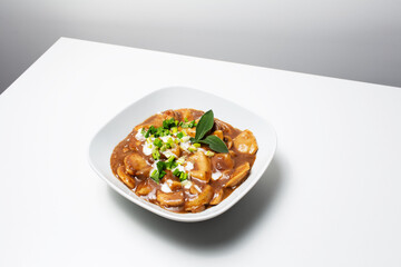 Vegan food. Homemade dumplings with potatoes and mushrooms in gravy, on white.