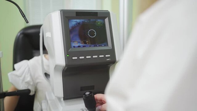 doctor examines child's eye on screen of autorefractometer. ophthalmic device.