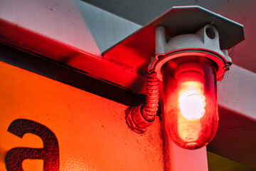 Closeup of a red warning light bulb on the wall