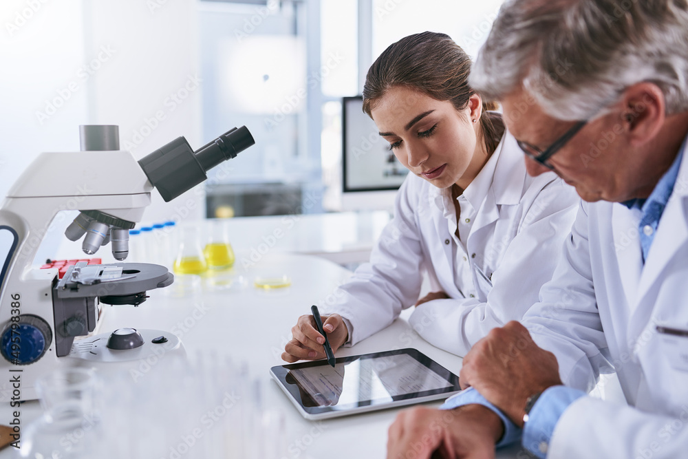 Poster making sense of their latest findings. shot of two scientists working together on a digital tablet i