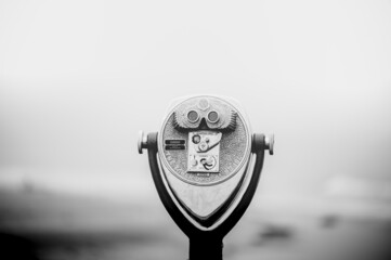 Grayscale shot of Coin-operated binoculars on blurred background. Newport Beach, California