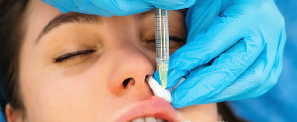 Young woman gets hyaluronic filler or botox cosmetic injection in lips, close up. Rejuvenating...