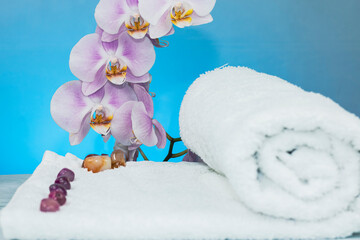Towels rolled with colored stones and orchids on a granite base