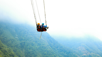 Two tourist are in a giant swing: famous tourist attraction swinging over a ravine in Ecuador