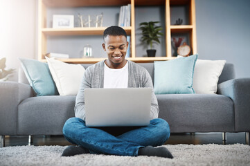 Connecting with an online world. Shot of a happy young man using a laptop while relaxing at home.