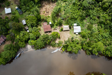 Top view of small houses in an indigenous community in the Amazon rainforest with canoes in the...