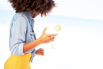 Beautiful exotic afro woman holding Gin Tonic in the beach. Good summer vibes.