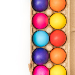 Colored easter eggs in brown carton on white background