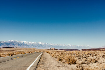 Side of a Road in the Desert with Snow Capped Mountains and Blue Sky