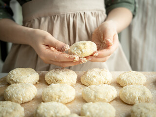 The girl makes cottage cheese pastries for breakfast.