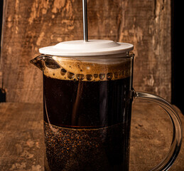 Coffee in french press with wooden background