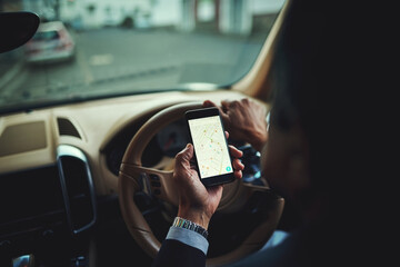 Getting there safely thanks to gps. Cropped shot of a businessman using his phones gps while driving a car.