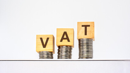 rising stacks of coins with the letters VAT on the wooden cubes, white background, business and finance concept