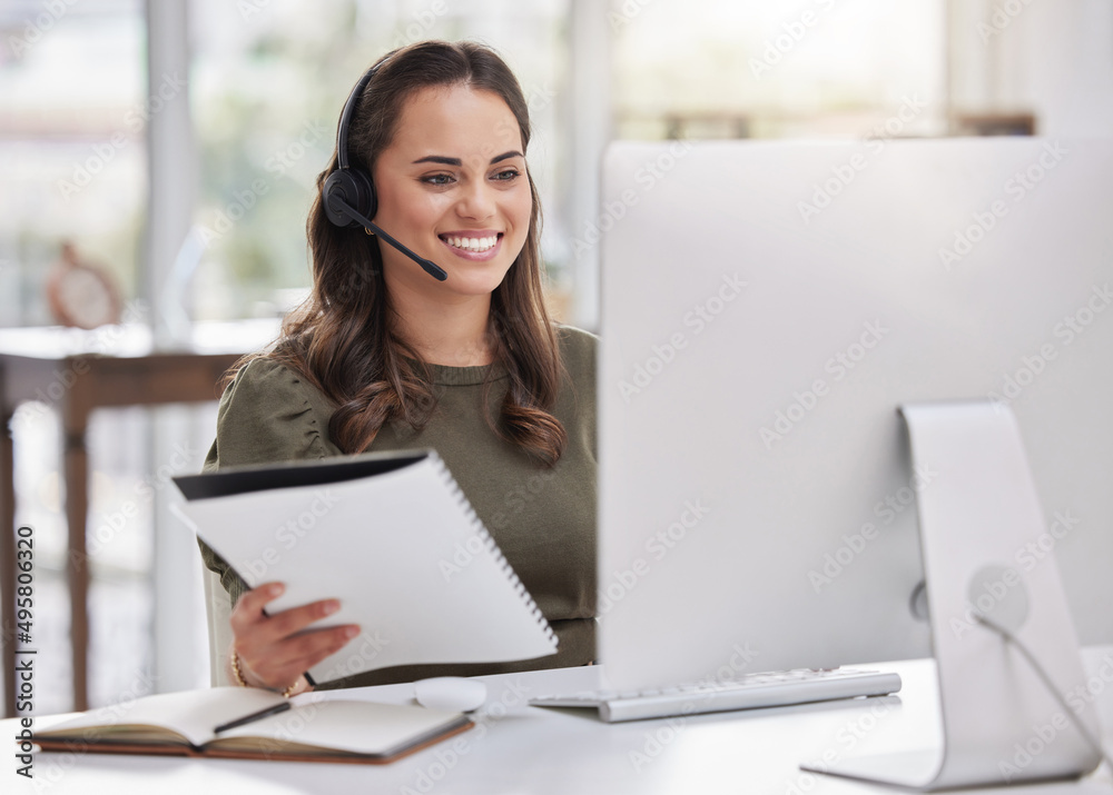 Aufkleber inputting new info onto the system. shot of a young call centre agent going through paperwork while 