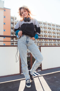 Happy caucasian teenage girl in the 90s enjoying her free time after school and listening to music. Back light. Vertical outdoor shot. High quality photo