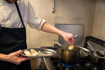 chef cuece tortelini pasta fresca con salsa tradicional y queso en cocina de restaurante italiano