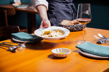 Obraz na płótnie Canvas plato de pasta fresca tortelini con queso parmesano y salsa en un restaurante italiano con copa de vino en una mesa servido por camarero