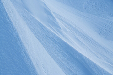 Snow texture. Wind sculpted patterns on snow surface. Wind in the tundra and in the mountains on the surface of the snow sculpts patterns and ridges (sastrugi). Arctic, Polar region. Winter background