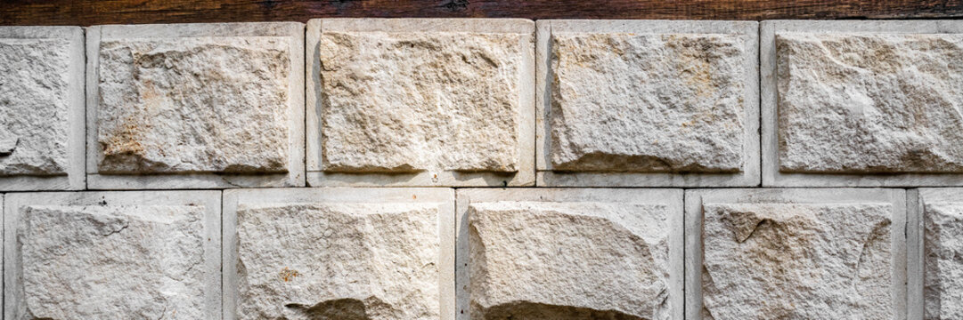 Wall lined with decorative stone. The rough surface of the stones. Beautiful masonry in a classic style. Wide panoramic texture for background and design.