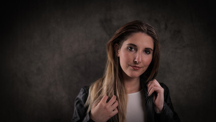 Close-up of a young attractive woman against dark grey background - studio photography