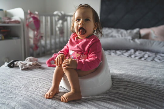 One small caucasian baby girl ten months sitting on the children's potty at home