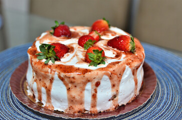 Um pequeno bolo de chantilly com geléia e morangos decorando