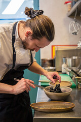 chef cocina plato de tempura de verduras con tinta de calamar y salsa de pimiento rojo en cocina de restaurante en un bol 